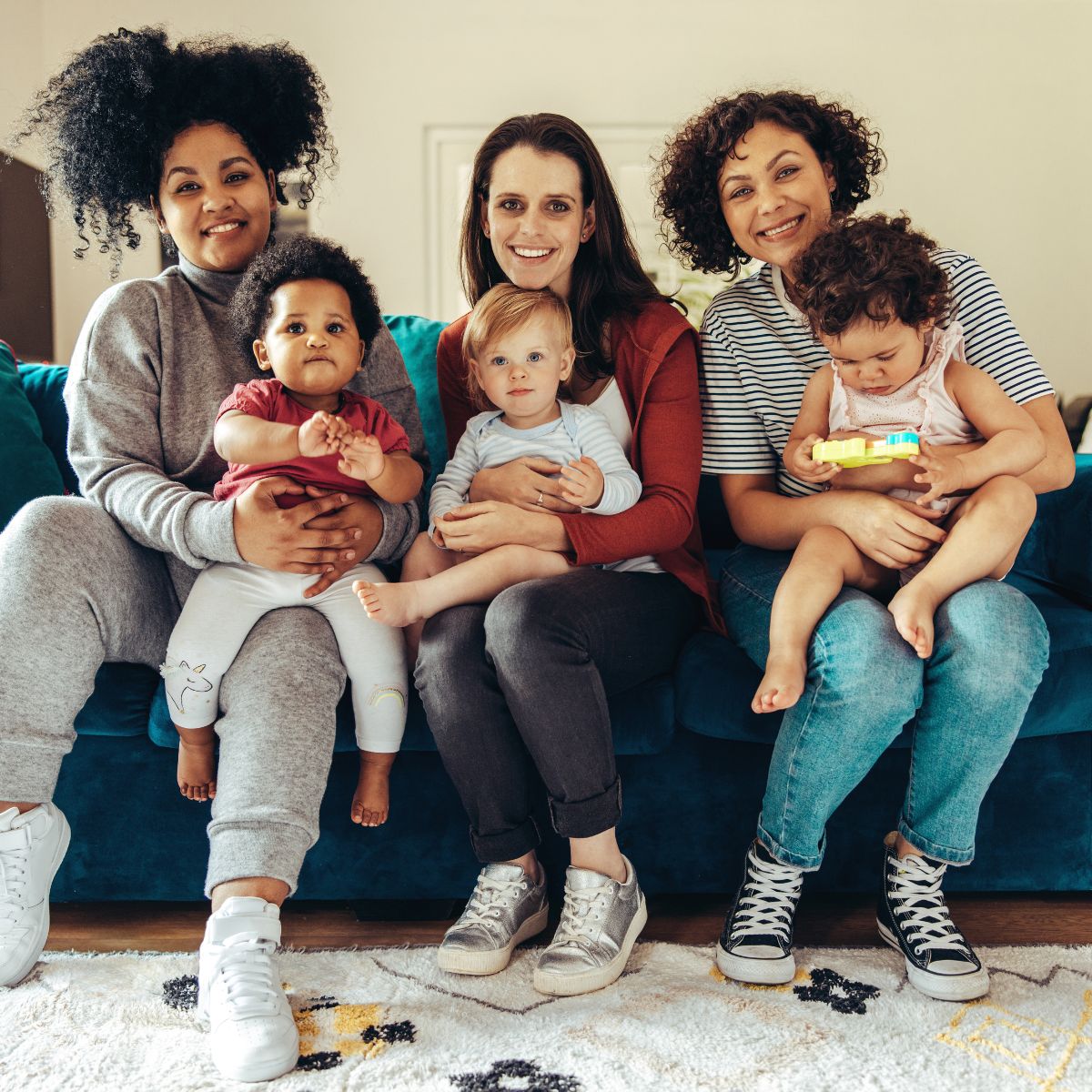 Three women sitting on a couch holding their children